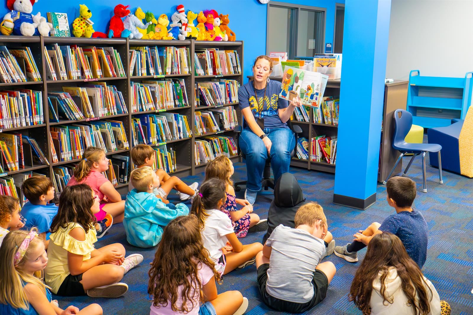 teacher reading a book in the library to the class